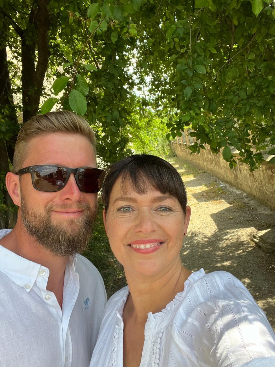 Nicole und Mathias, eure Gastgeber im Ilsehof in Osterwieck, lächeln in die Kamera unter einem grünen Blätterdach