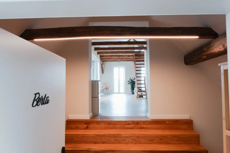 Blick von außerhalb der Ferienwohnung Berta auf den Eingangsbereich und weiter in den hellen Wohn- und Essbereich mit Holztreppe