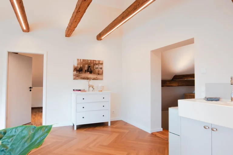 Wohnbereich der Ferienwohnung Berta auf dem Ilsehof mit Kommode, Wandbild und Zugang zu Schlafzimmer 1 und dem Eingangsbereich