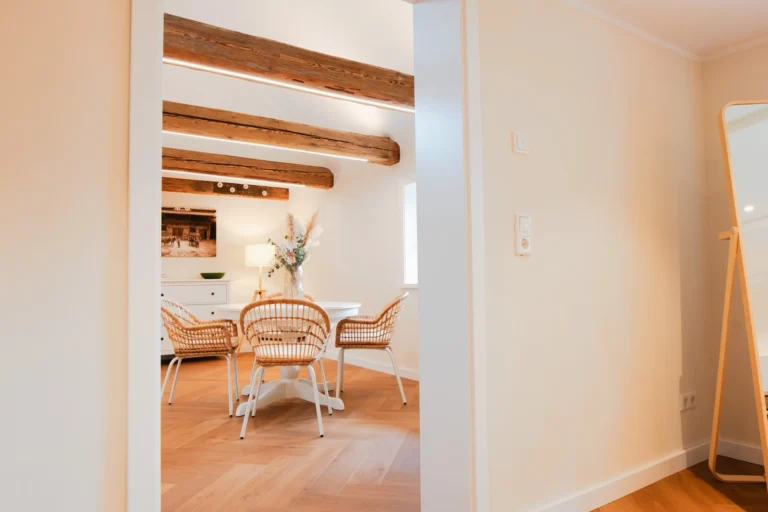 Schlafzimmer der Ferienwohnung Anna auf dem Ilsehof mit Doppelbett, offener Holz-Kleiderstange und sichtbaren Deckenbalken