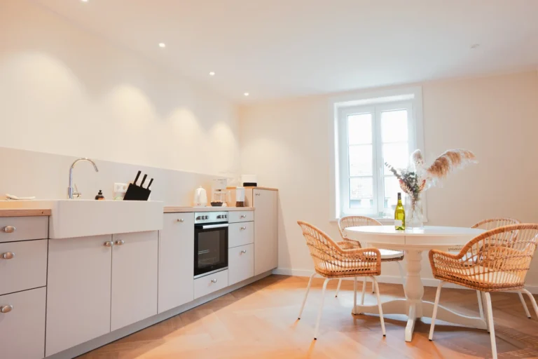 Küche der Ferienwohnung Ruth mit großer Arbeitsfläche, Spüle und Essbereich mit Rattan-Stühlen.