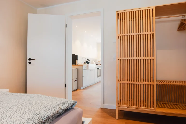 Schlafzimmer der Ferienwohnung Ruth mit Doppelbett und Holz-Kleiderschrank, daneben Tür zur Küche.