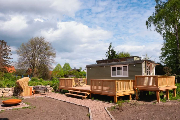 Außenansicht des Tiny House Mimi mit großer Holzterrasse und Gartenbereich