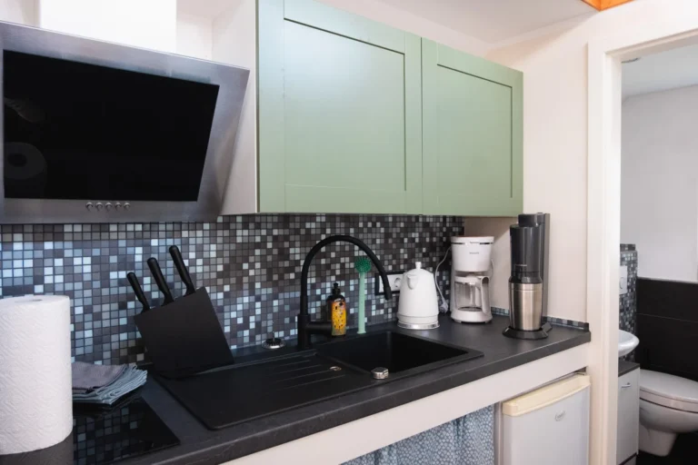Detailaufnahme der Küche im Tiny House Mimi mit Kaffeemaschine, Wasserkocher und schwarzer Spüle