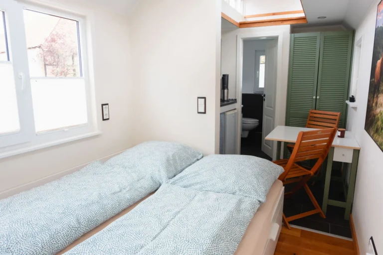 Schlafzimmer im Tiny House Mimi mit Doppelbett und Blick zur Küche