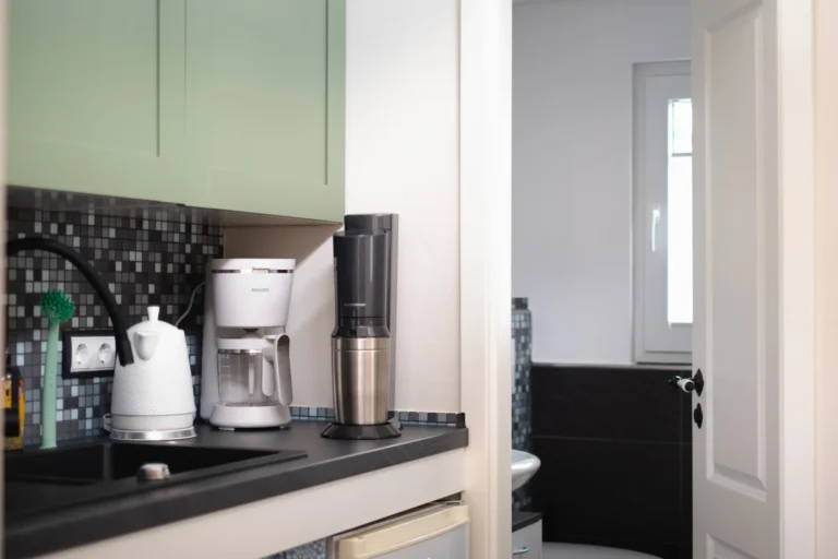 Küchenzeile im Tiny House Mimi mit Wasserkocher, Kaffeemaschine und Blick ins Bad
