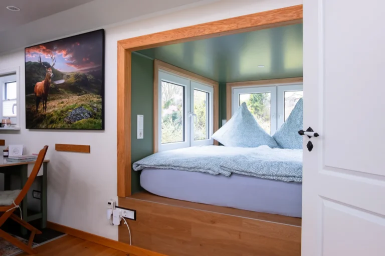 Schlafnische mit grünen Wänden und Holzrahmen im Tiny House Mimi – Ilsehof Harz