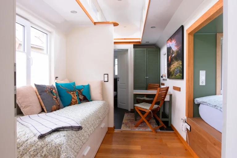 Innenraum des Tiny House Mimi auf dem Ilsehof – Sofa, Essbereich und Schlafnische mit Doppelbett auf 21 m²