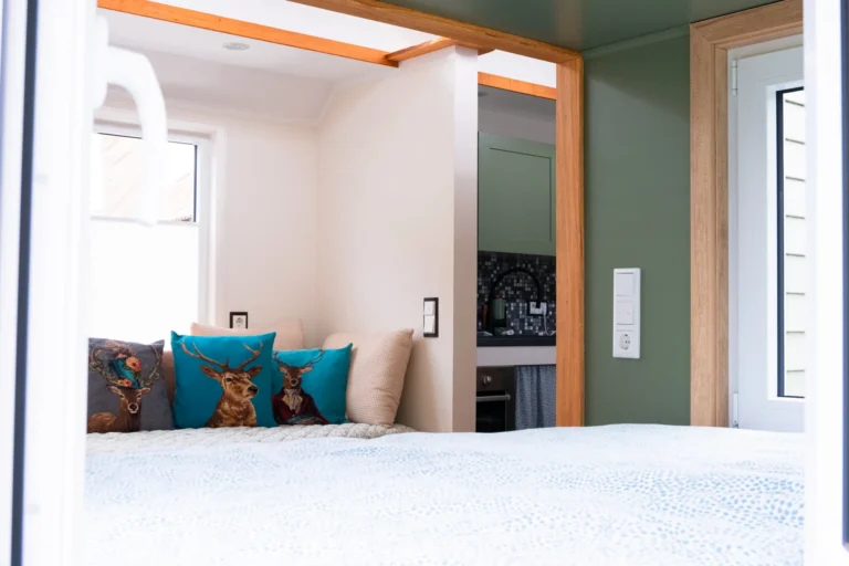 Blick vom Bett auf Sitzbereich und Küchenzeile mit Mosaikfliesen – Tiny House Mimi, Ilsehof Osterwieck