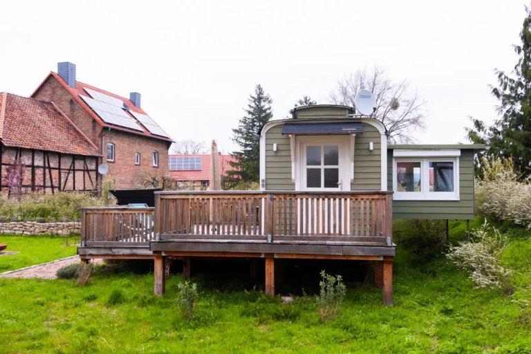 Tiny House Mimi Seitenansicht mit Holzterrasse, umgebauter Bauwagen auf dem Ilsehof bei Osterwieck, Harz